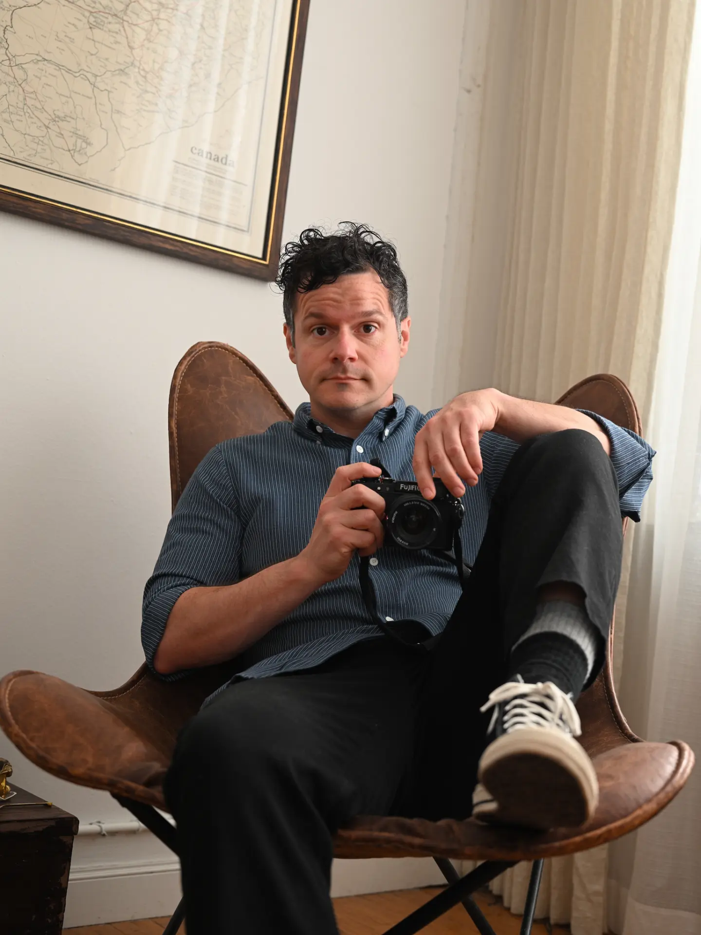 James R.C. Smith sitting in a leather chair holding a camera